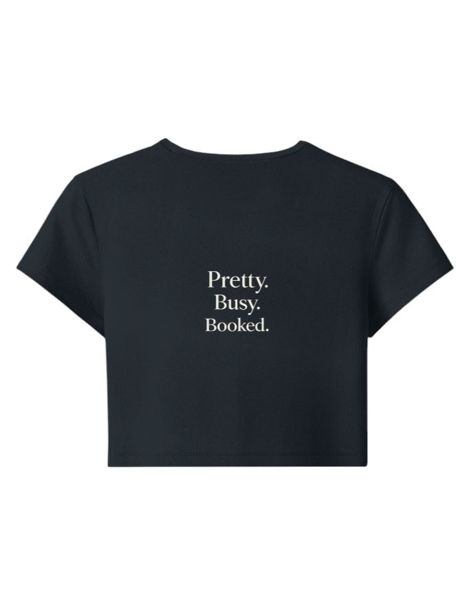 Fourthwave black cropped baby tee with "Pretty. Busy. Booked." text in white, made of 95% cotton and 5% spandex.