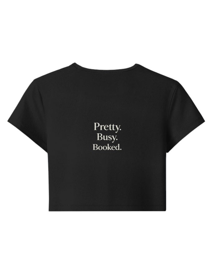 Fourthwave black cropped baby tee with "Pretty. Busy. Booked." text, made of 95% cotton and 5% spandex blend.