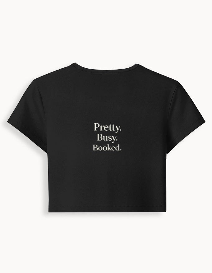 Fourthwave black cropped baby tee with "Pretty. Busy. Booked." text, made from 95% cotton and 5% spandex blend.