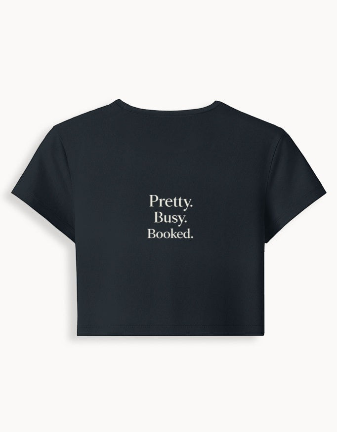 Fourthwave black cropped baby tee with "Pretty. Busy. Booked." text in white. Made from 95% cotton and 5% spandex blend.