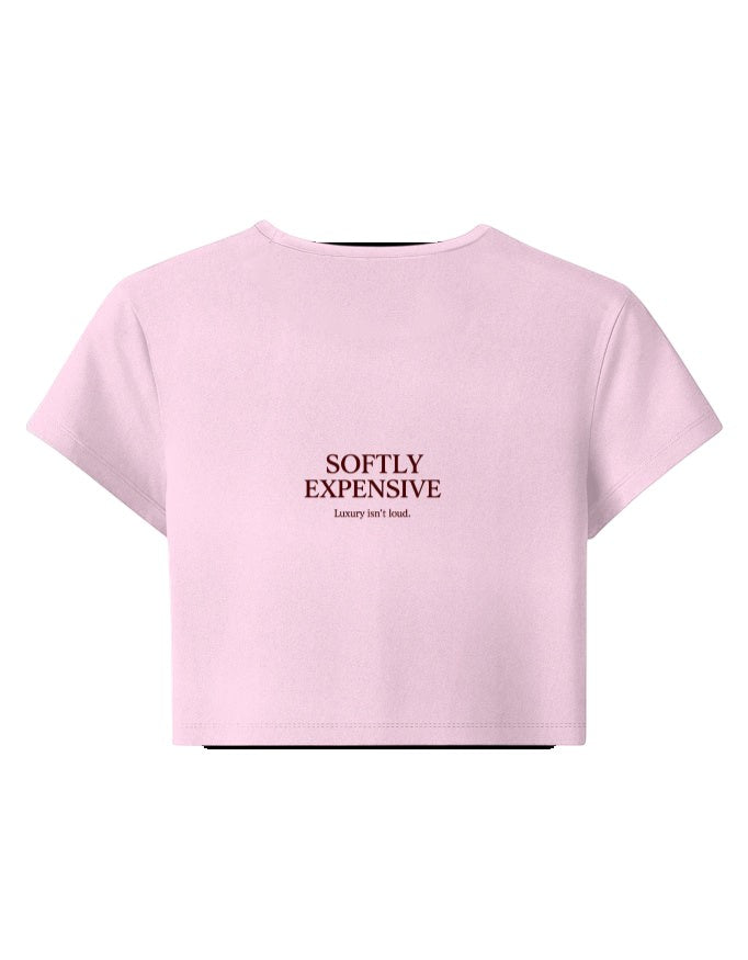 Fourthwave pastel pink cropped t-shirt with crew neck and short sleeves, featuring text graphic "SOFTLY EXPENSIVE Luxury isn't loud."
