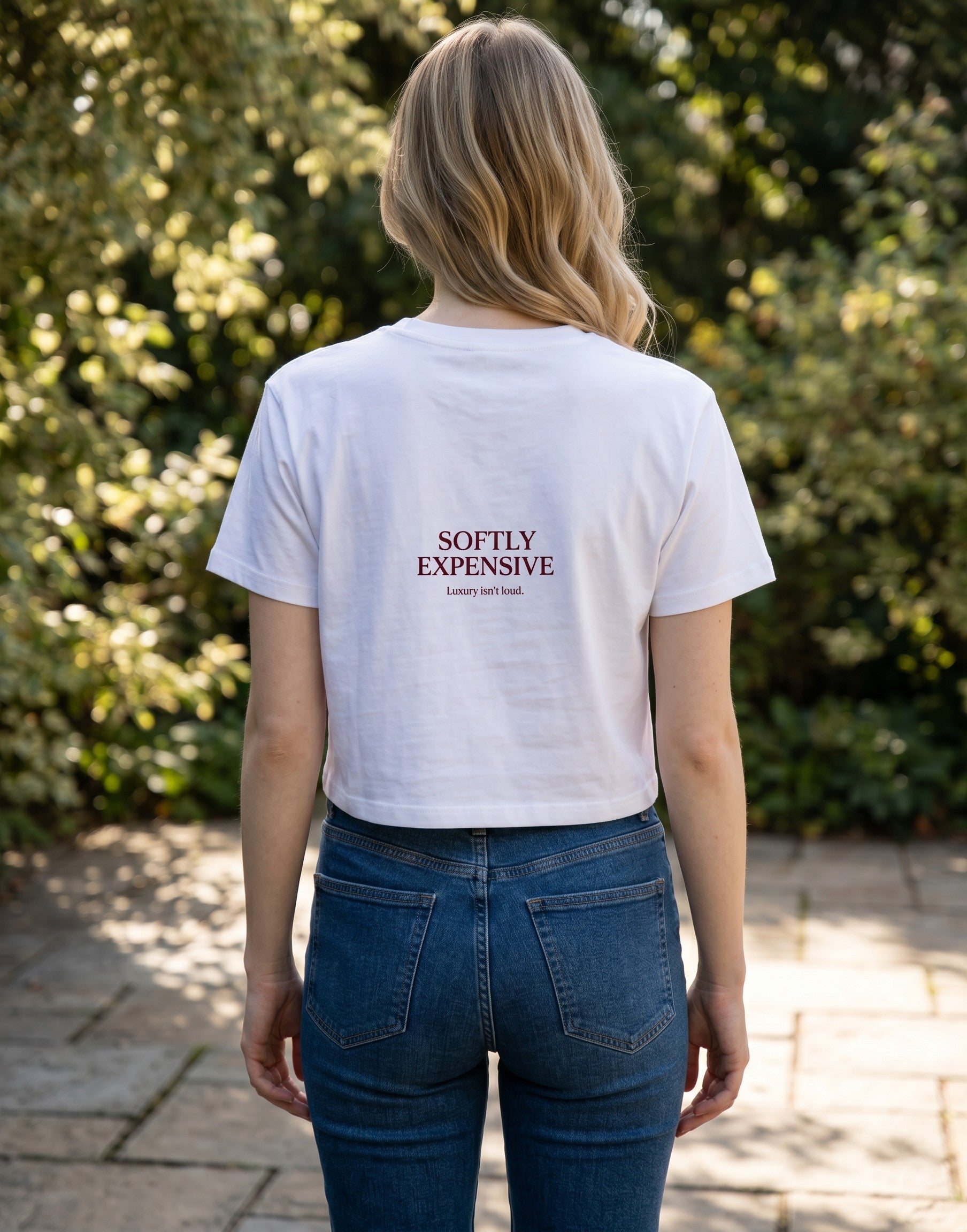 Fourthwave white cropped t-shirt with "SOFTLY EXPENSIVE Luxury isn't loud." text graphic on chest.