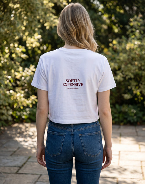 Fourthwave white cropped t-shirt with "SOFTLY EXPENSIVE Luxury isn't loud." text graphic on chest.